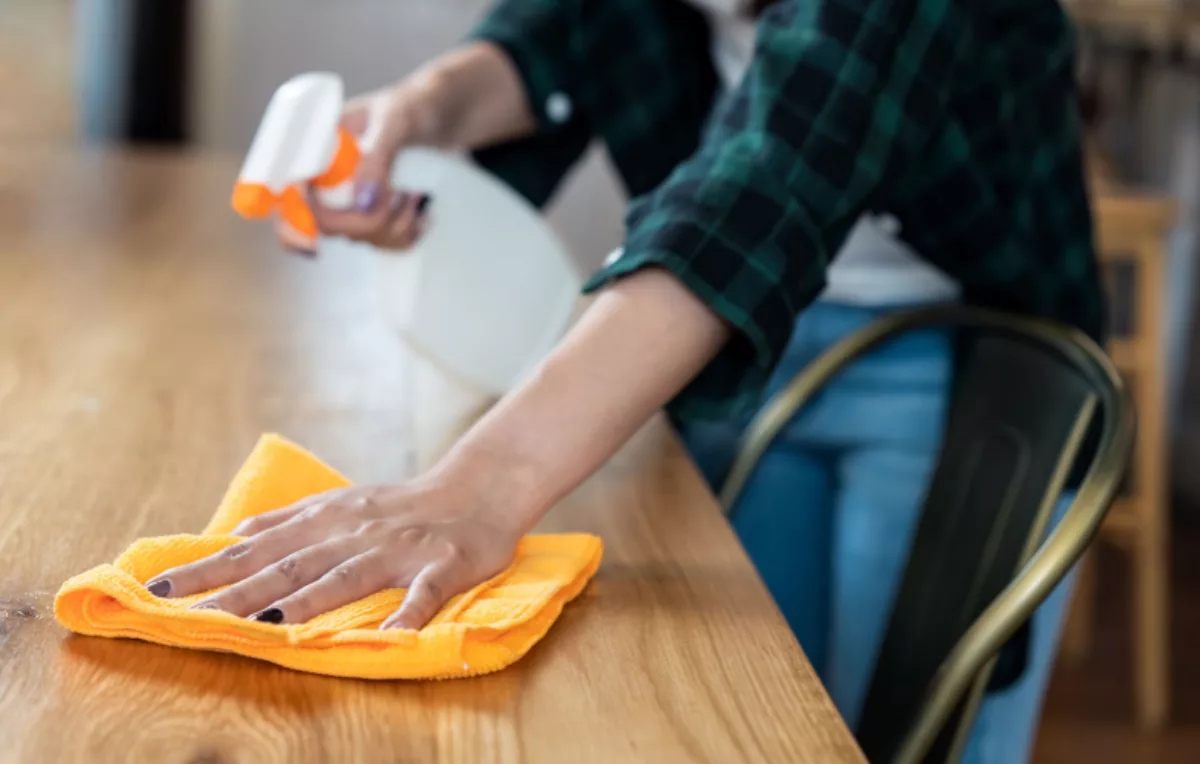 A woman cleaning a table with a cloth