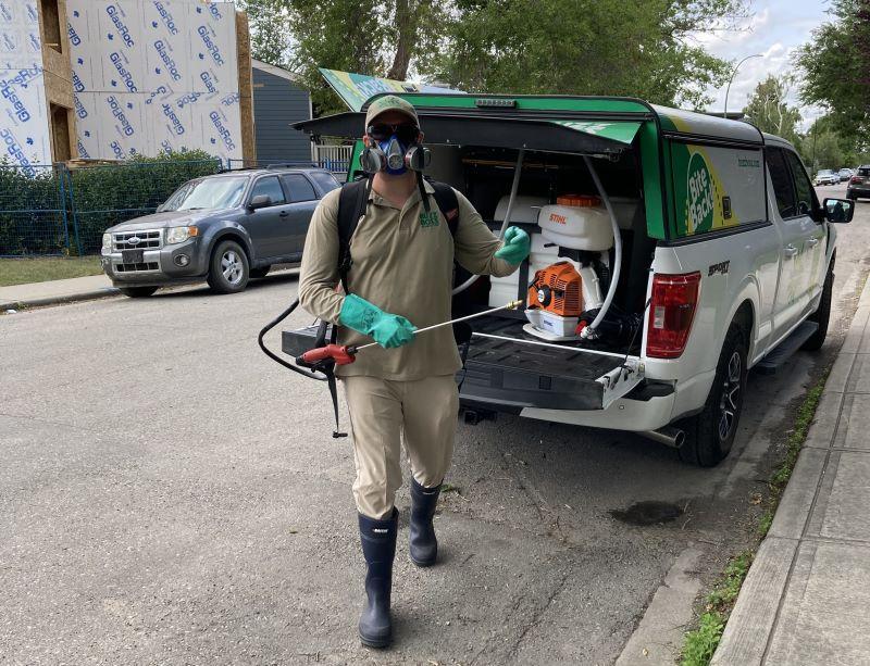 Buzz Boss Technician fully equipped for mosquito spraying by Buzz Boss truck
