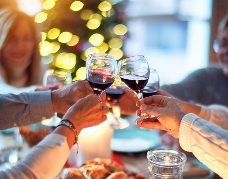 People holding high their wine glasses at a holiday dinner